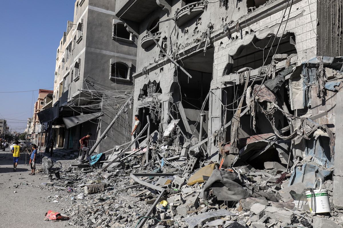 Palestinesi e le rovine di una casa dopo un raid israeliano nella città di Rafah, Sud della Striscia di Gaza, 12 ottobre 2023